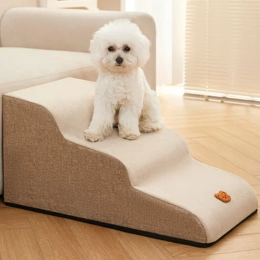 Kleiner weißer Hund auf beiger Haustiertreppe aus Stoff neben Sofa im Wohnzimmer.