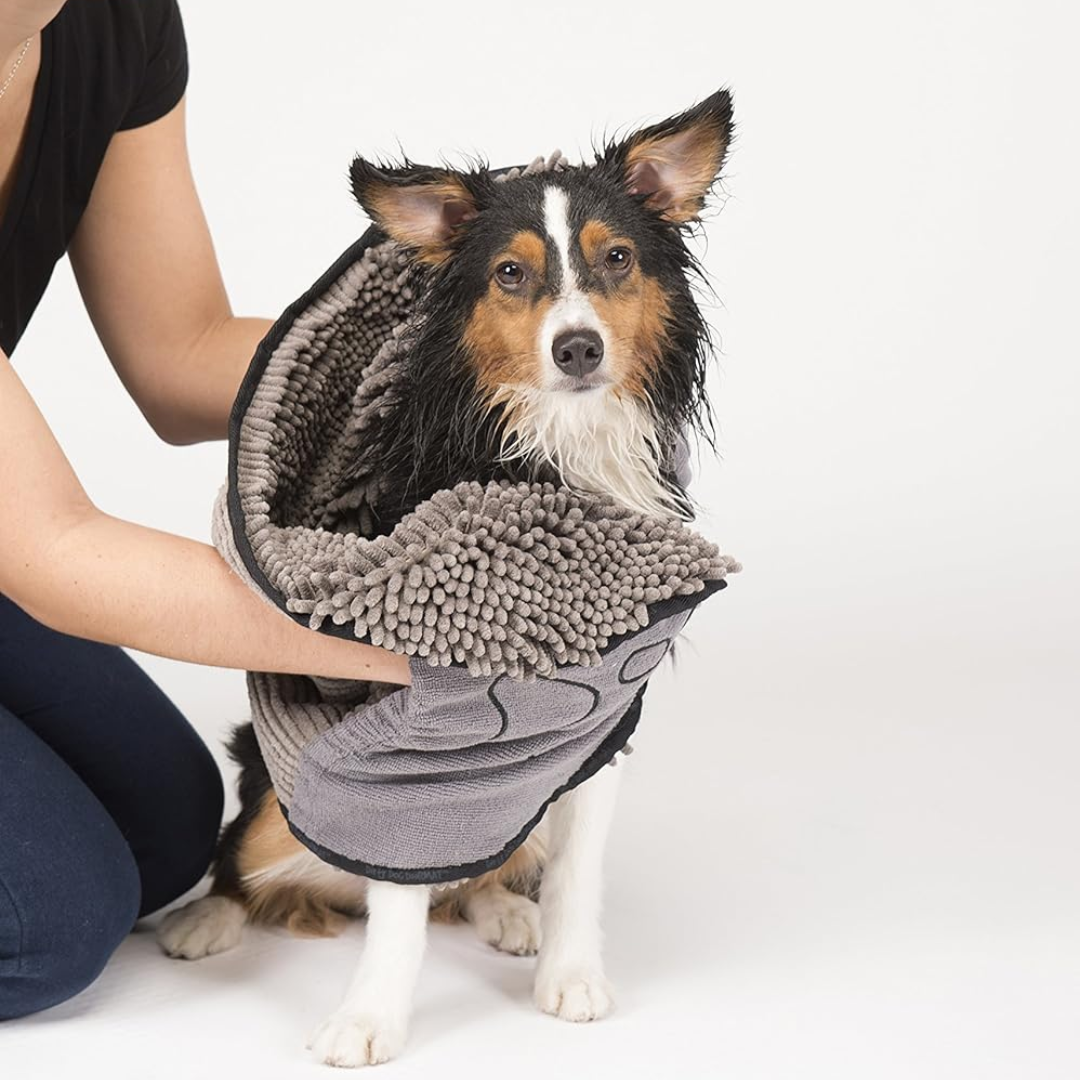 Nasser Hund wird mit grauem Mikrofaser-Handtuch abgetrocknet, Haustierpflege, Hundebadetuch.