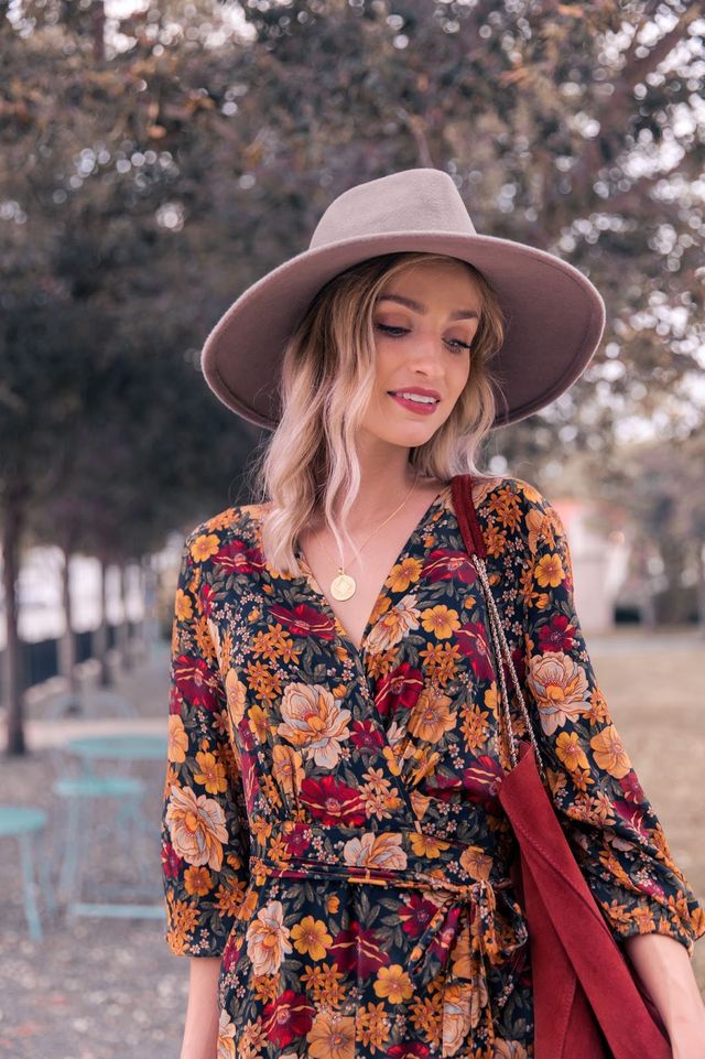 Frau mit grauem Hut und geblümtem Kleid im Freien, Herbstmode, stilvoll, lässig.