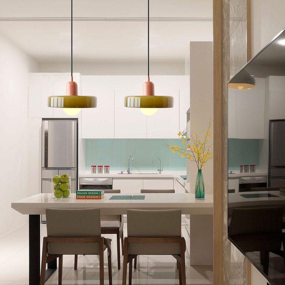 Moderne Küche mit weißen Schränken, Insel, Hängelampen, Edelstahlgeräten, minimalistisches Design.