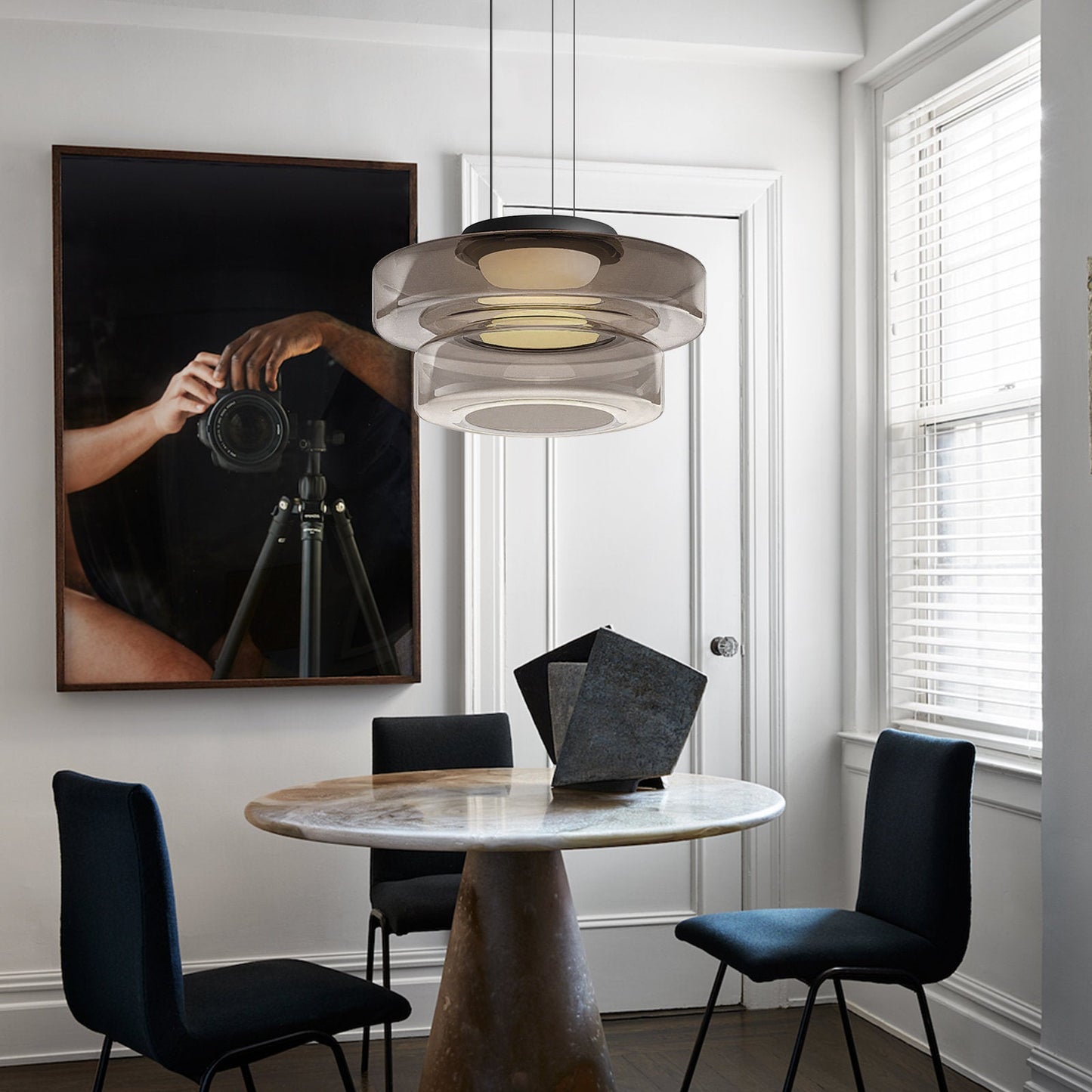 Moderne Hängelampe über rundem Marmortisch in elegantem Esszimmer mit Kunstwerk an der Wand.