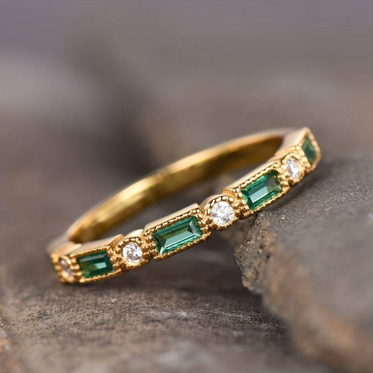 Goldener Ring mit grünen Smaragden und Diamanten, elegantes Schmuckdesign, Nahaufnahme.