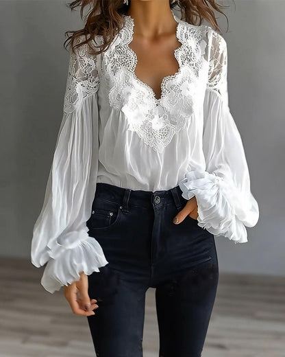 Vit blus i halvfigur framifrån med spetsad V-ringning, vida ärmar och svarta jeans 3