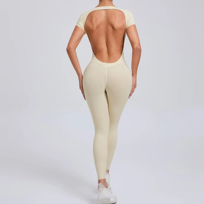 Frau in beigefarbenem, rückenfreiem Jumpsuit, Sportbekleidung, Ganzkörperansicht.