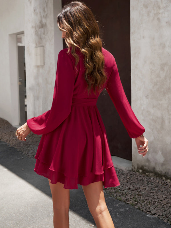 Frau in rotem Chiffonkleid mit langen Ärmeln, elegantes Design, draußen bei Tageslicht.