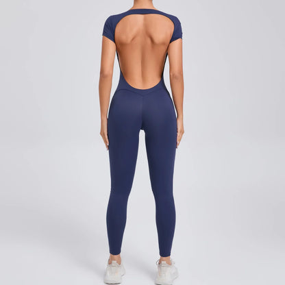 Frau in dunkelblauem, rückenfreiem Jumpsuit, Sportbekleidung, Ganzkörperansicht von hinten.