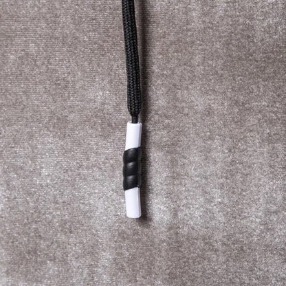 Schwarze und weiße Kordelstopper auf grauem Stoffhintergrund, Textilzubehör.