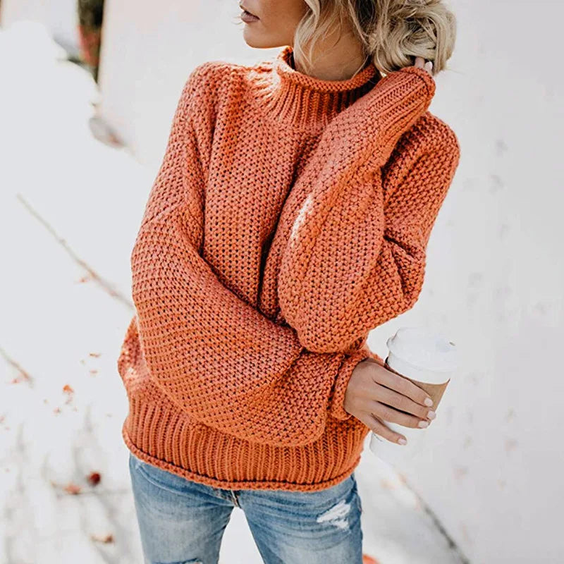 Frau in orangefarbenem Strickpullover hält Kaffeebecher, lässige Herbstmode, Jeans.