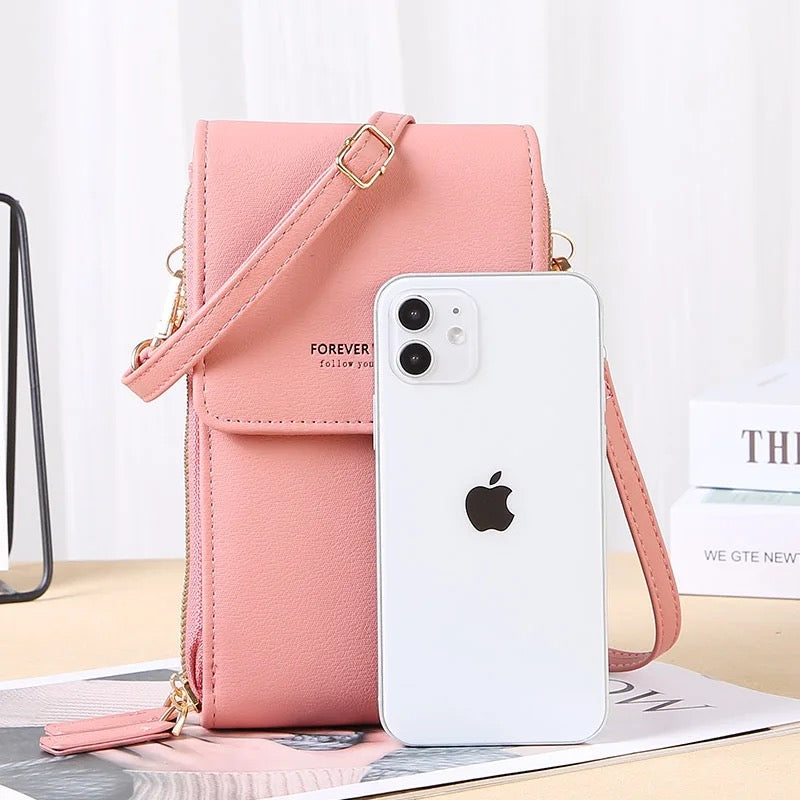 Rosa Handytasche aus Leder mit Schulterriemen, neben weißem Smartphone, modisch und praktisch.