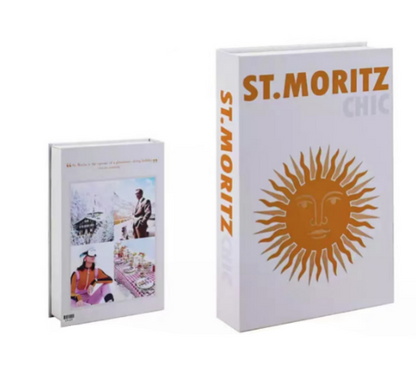 Zwei Bücher: "St. Moritz Chic" mit Sonnenmotiv, weißer Einband, und ein kleineres Buch daneben.
