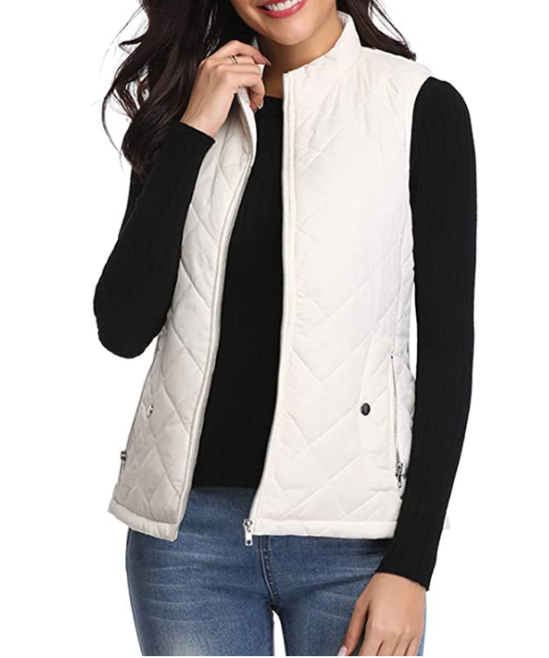 Frau trägt weiße Steppweste, ärmellos, Reißverschluss, über schwarzem Pullover, modisch, casual.