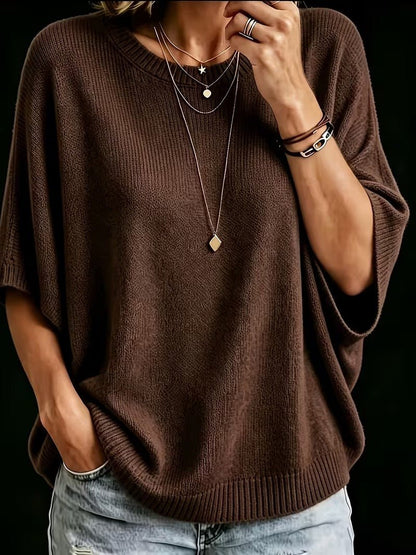 Närbild på brun stickad topp med batwing-ärmar och rund hals, burna med lagda halsband och armband. 17
