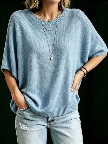 Blå stickad topp framifrån på modell med ena handen i jeansfickan och den andra på höften. 15