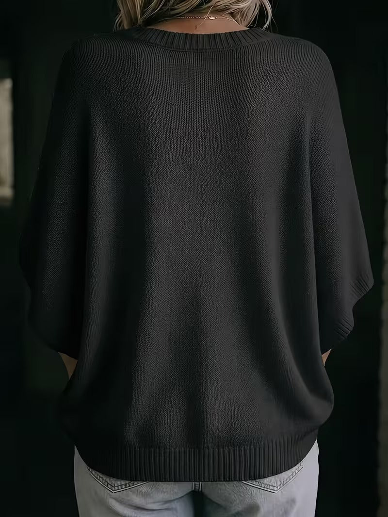 Baksidan av den svarta stickade toppen med ribbad halsringning och ribbad nederkant, buren med ljusgrå jeans. 28