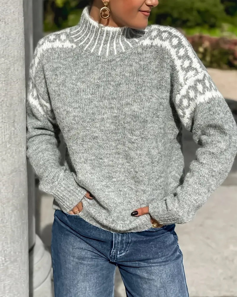 Grå tjockstickad tröja med polokrage och vita mönsterkanter på axlarna, buren med jeans utomhus. 5