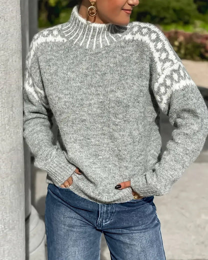 Grå tjockstickad tröja med polokrage och vita mönsterkanter på axlarna, buren med jeans utomhus. 5