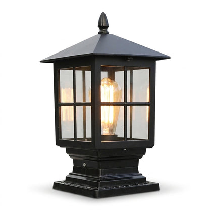 Svart pelarlampa med fyrkantigt tak, rutindelat glas och tänd glödlampa, fotograferad snett framifrån mot vit bakgrund. 1