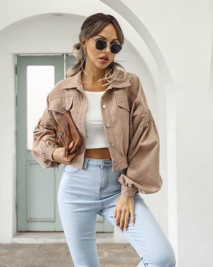 Frau in beiger Cordjacke und blauer Jeans, modisch, lässig, Sonnenbrille, weißes Top.