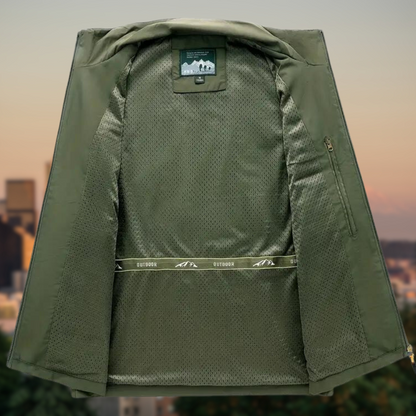 Grüne Outdoor-Jacke mit Netzfutter, geöffnet, vor städtischem Hintergrund.