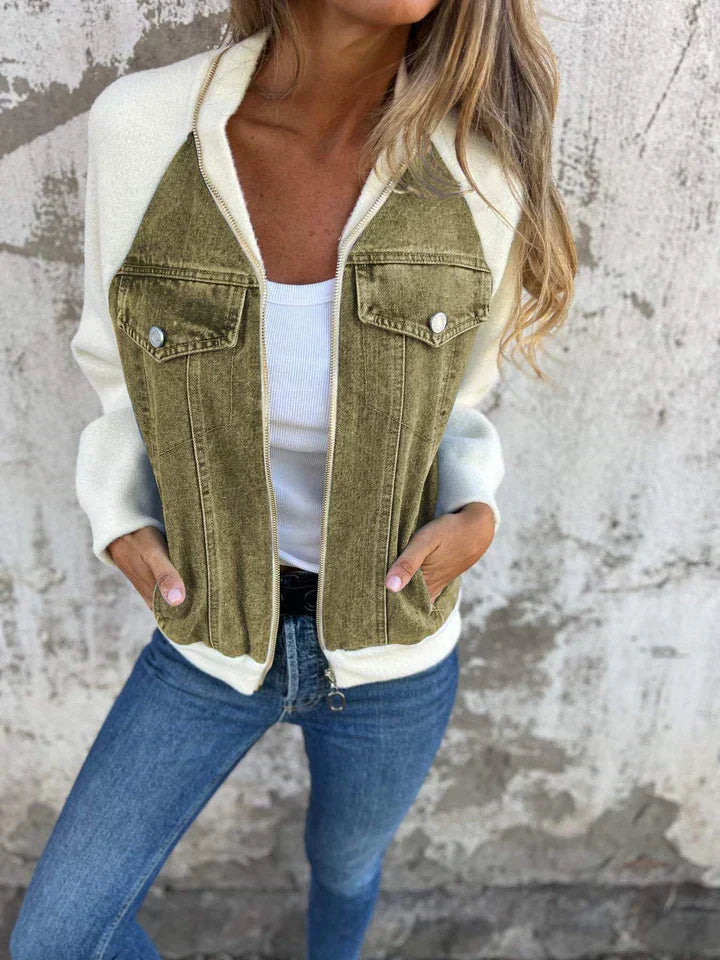 Frau in olivgrüner Jeansjacke und blauer Jeans vor Betonwand.