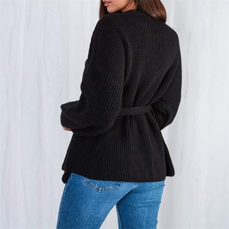 Frau trägt schwarzen Strickmantel mit Gürtel, Wintermode, Damenbekleidung, Rückansicht.