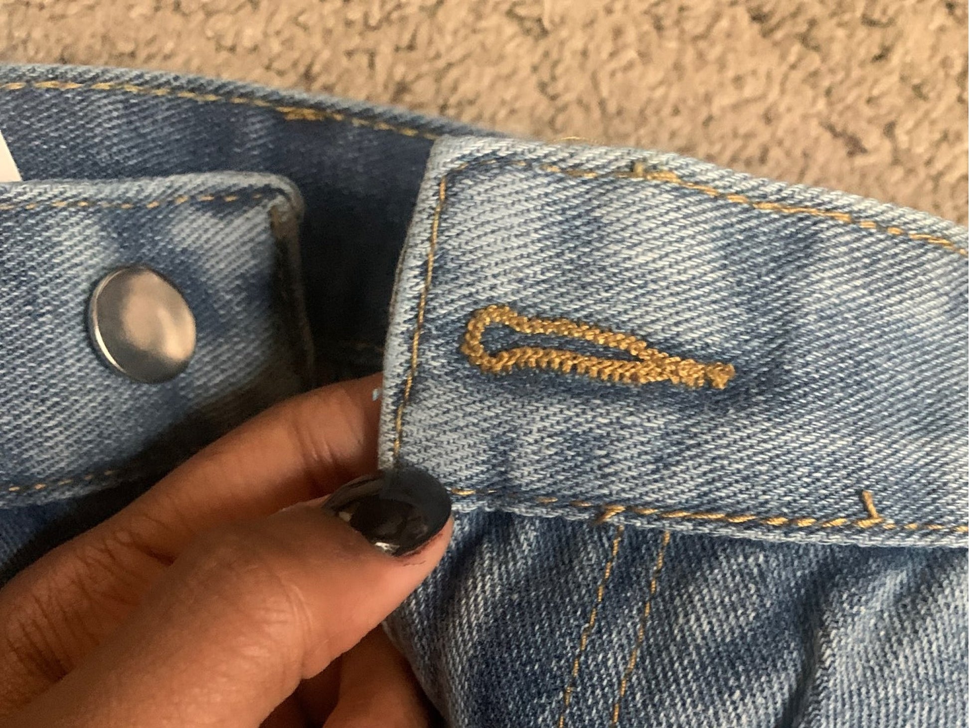 Nahaufnahme einer blauen Jeans mit goldener Naht und Knopf, Denim, Mode, Kleidung, Detailansicht.