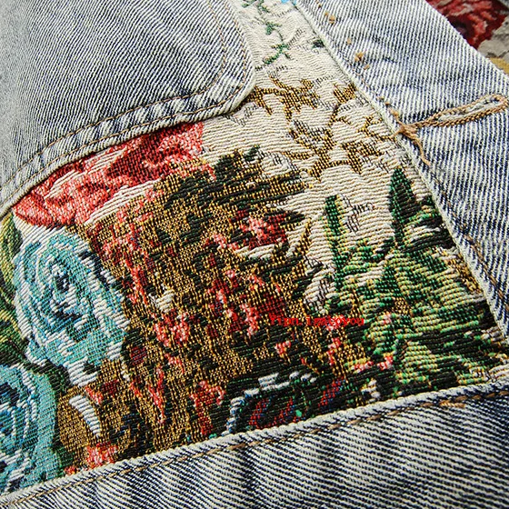 Nahaufnahme bestickte Jeansjacke mit floralen Mustern, Vintage-Stil, bunte Blumenstickerei.