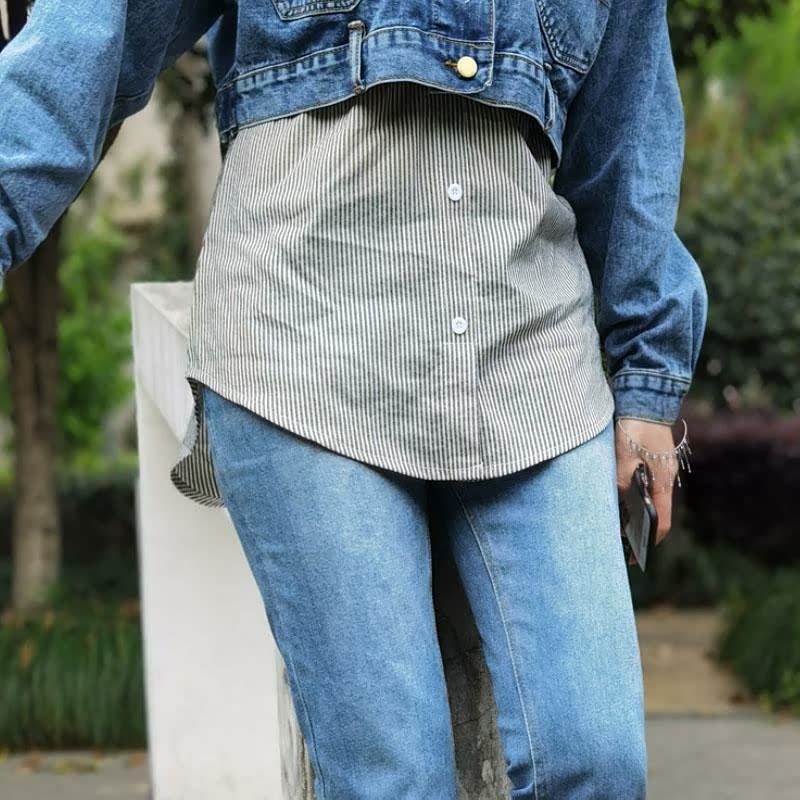 Person in blauer Jeansjacke und Jeans, gestreiftes Hemd, draußen im Park.