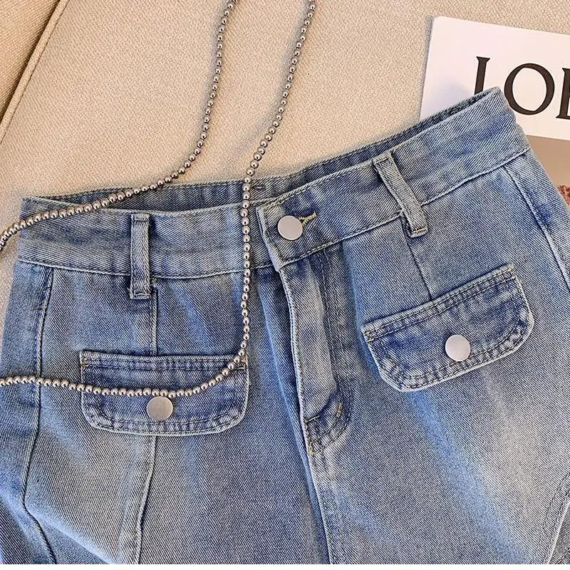Blaue Jeans mit Taschen und Kettenriemen auf beigem Hintergrund, modisch, lässig.
