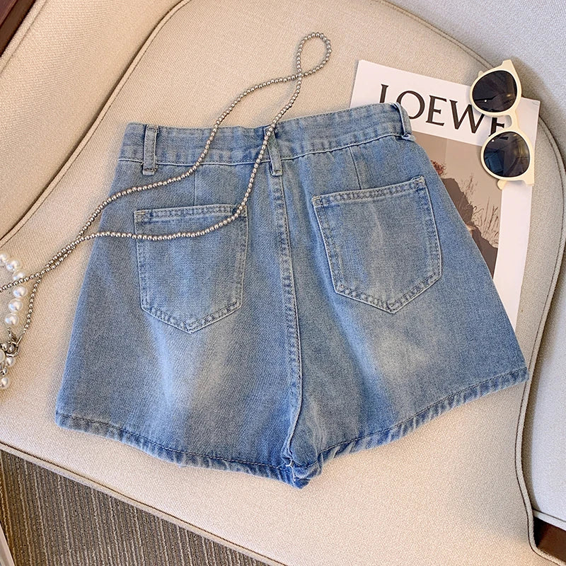 Damen Jeansshorts blau, lässig, Sommermode, auf Sofa mit Sonnenbrille und Magazin.