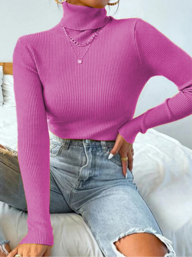 Frau in pinkem Rollkragenpullover und zerrissenen Jeans auf Bett sitzend, modisch, lässig.