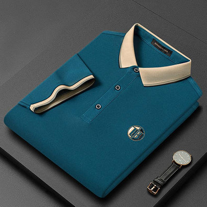Dunkelgrünes Herren-Poloshirt mit beigem Kragen, Knöpfen und Uhr auf grauem Hintergrund.