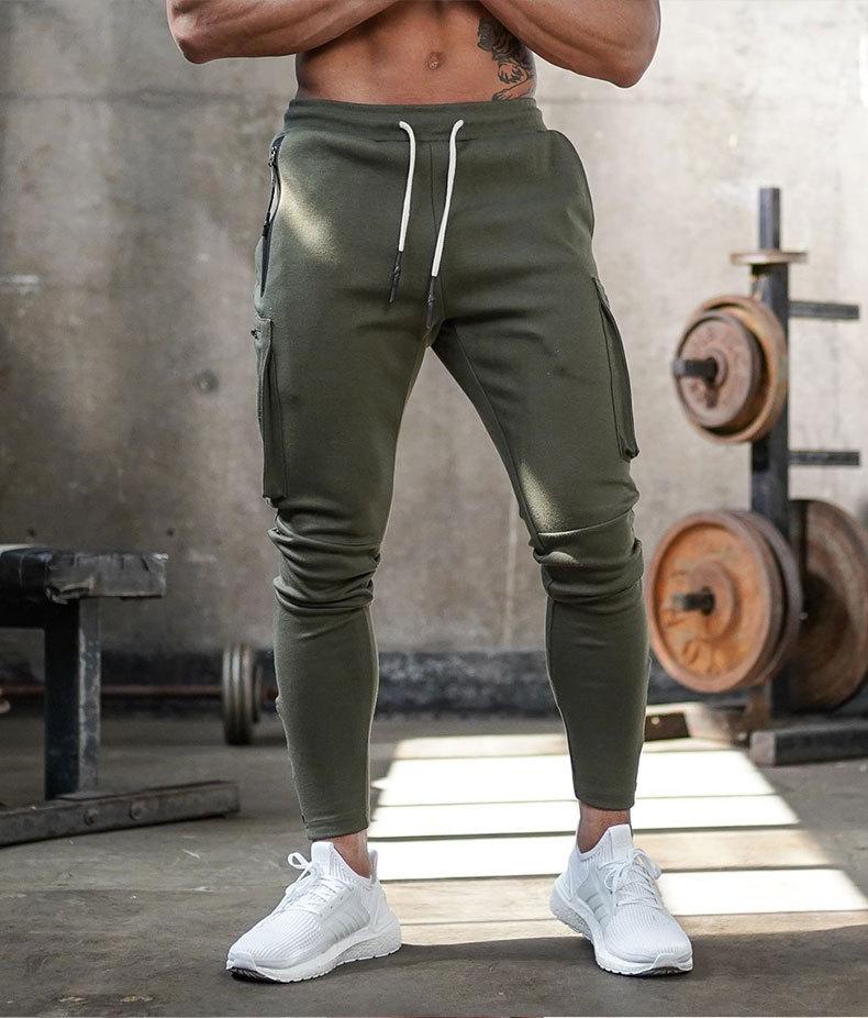 Mann in olivgrüner Jogginghose, Fitnessstudio, weiße Sneaker, Sportbekleidung, Training.