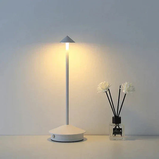 Moderne weiße LED-Tischlampe neben Duftstäbchen in Vase, minimalistisch, energiesparend.