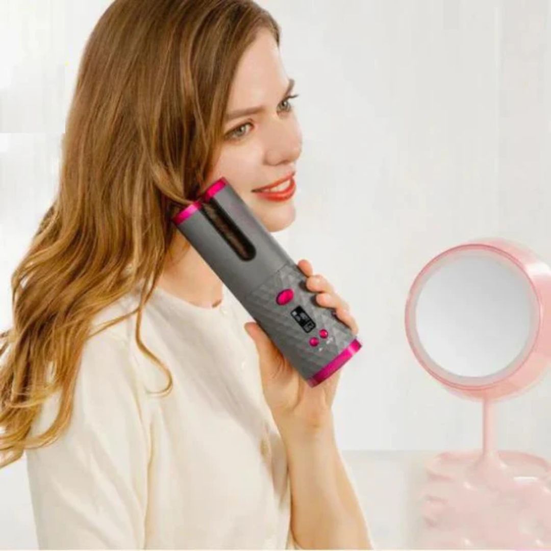 Frau benutzt kabellosen automatischen Lockenstab, grau-rosa, vor Spiegel.