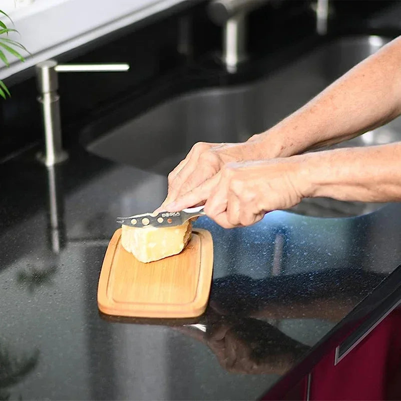 Person schneidet Käse auf Holzbrett in moderner Küche, schwarzer Granit-Arbeitsplatte.