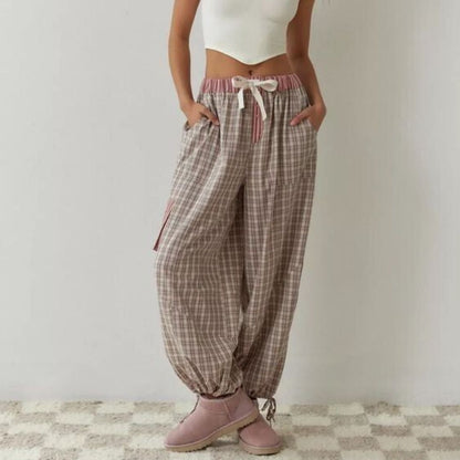 Frau in karierter Jogginghose, weißem Top, rosa Stiefeln; lässige Damenmode, bequem, modern.