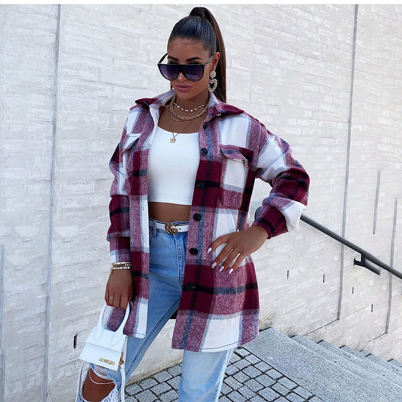 Frau in karierter Jacke, weißem Top, zerrissenen Jeans, Sonnenbrille, hält weiße Handtasche.