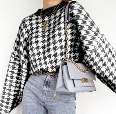 Frau mit schwarz-weißem Hahnentritt-Pullover, blauer Tasche und Jeans, modisch, elegant.