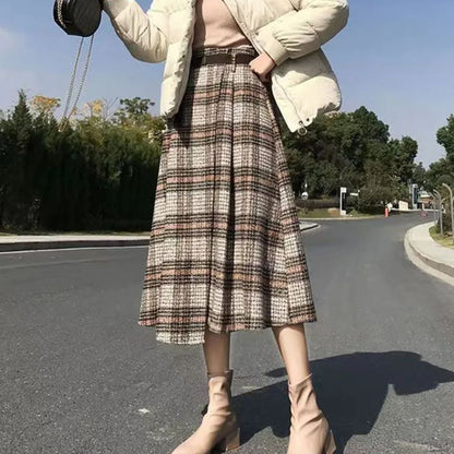 Frau in kariertem Rock und beiger Jacke auf Straße, Herbstmode, stilvolle Stiefeletten.