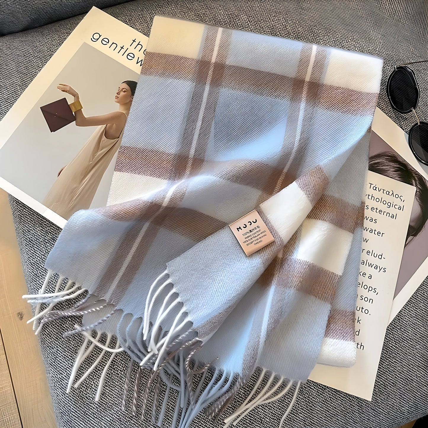 Kariertes Kaschmirschal in Weiß und Beige auf grauem Sofa, modisches Accessoire.