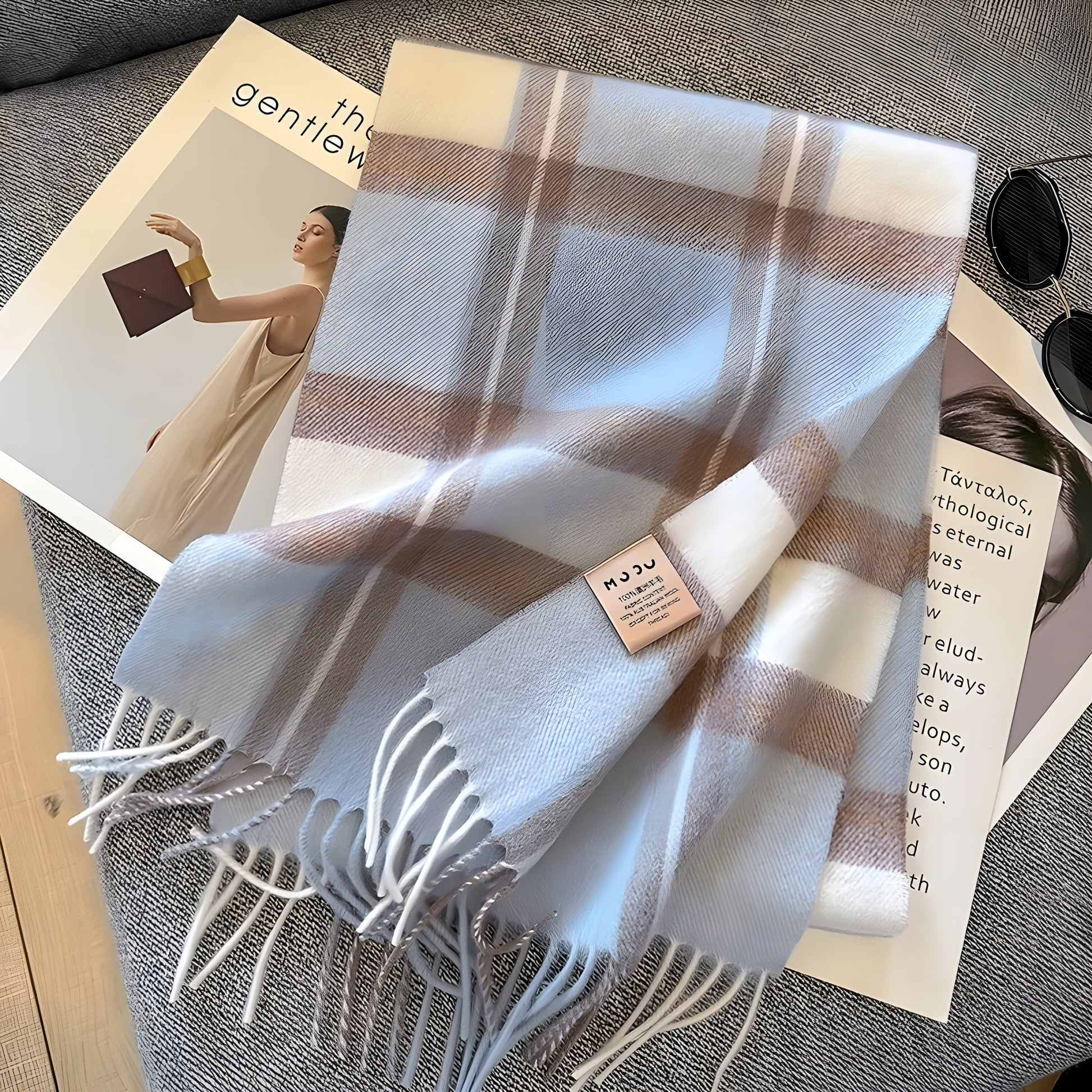 Kariertes Kaschmirschal in Weiß und Beige auf grauem Sofa, modisches Accessoire.