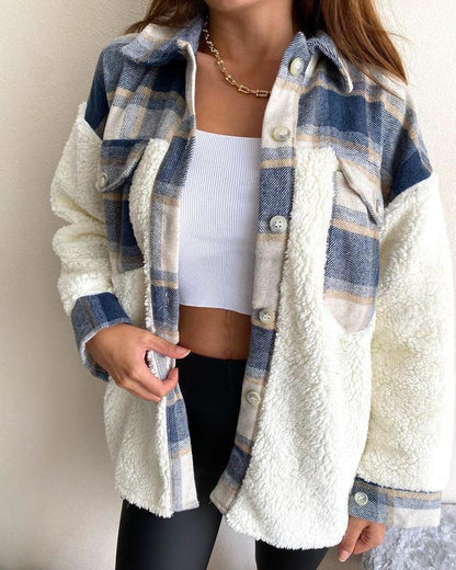 Frau trägt karierte Fleecejacke, blau-weiß, mit Knöpfen, über weißem Top.