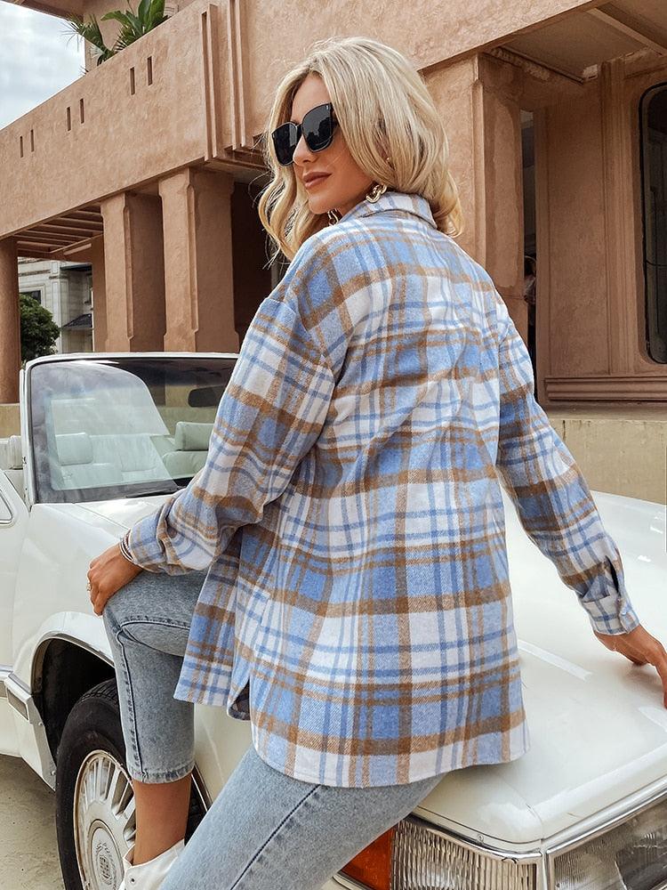 Frau in kariertem Hemd und Jeans sitzt auf weißem Cabrio, blonde Haare, Sonnenbrille.