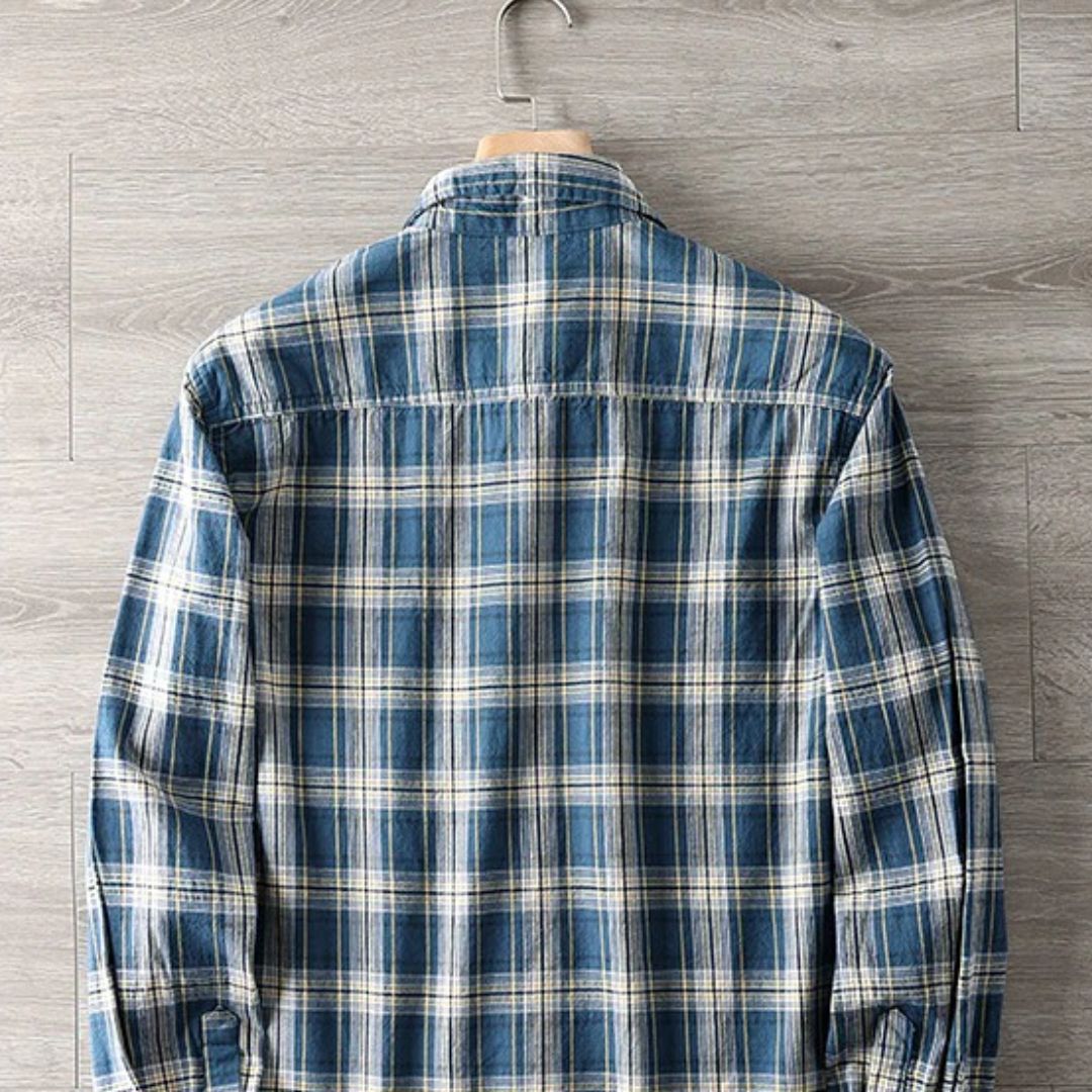 Blau-weiß kariertes Herrenhemd aus Baumwolle, langärmelig, lässig, auf Holzkleiderbügel.