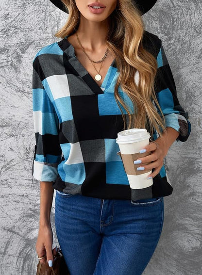 Frau in blau-schwarz kariertem Hemd, hält Kaffeebecher, trägt Jeans und Hut.