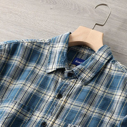 Blau kariertes Herrenhemd aus Baumwolle auf Holzkleiderbügel, modisch und lässig.