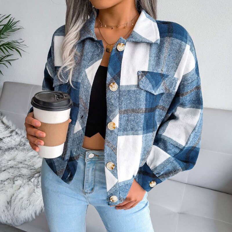 Frau in blau-weiß karierter Jacke hält Kaffeebecher, modische Freizeitkleidung.
