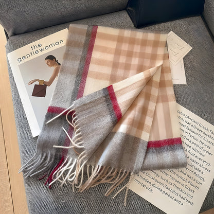 Beigefarbener Karoschal aus Wolle mit Fransen, auf grauem Sofa liegend, neben Zeitschriften.