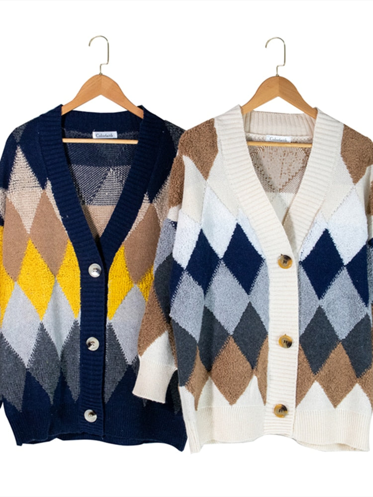 Zwei Strickjacken mit Rautenmuster, blau-gelb und beige-blau, auf Holzkleiderbügeln.